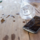 Mobiltelefon auf einem Tisch, das durch Wasser aus einem umgekippten Glas beschädigt wurde