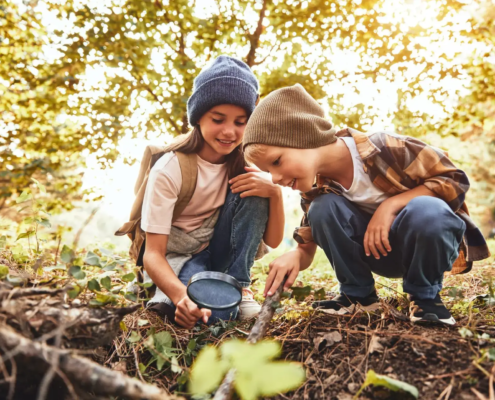 Kinderunfallversicherung Bestmögliche Absicherung für Ihr Kind 2 Kinder spielen im Wald und untersuchen den Boden