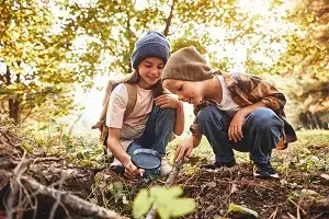 2 Kinder spielen im Wald und untersuchen den Boden
